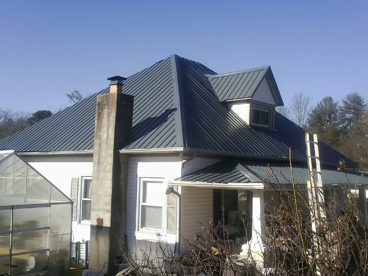 Dark blue standing seam metal roof on a white farmhouse with dormer — Slate & Tile Roof Repair by Roofing Brothers in Tompkinsville