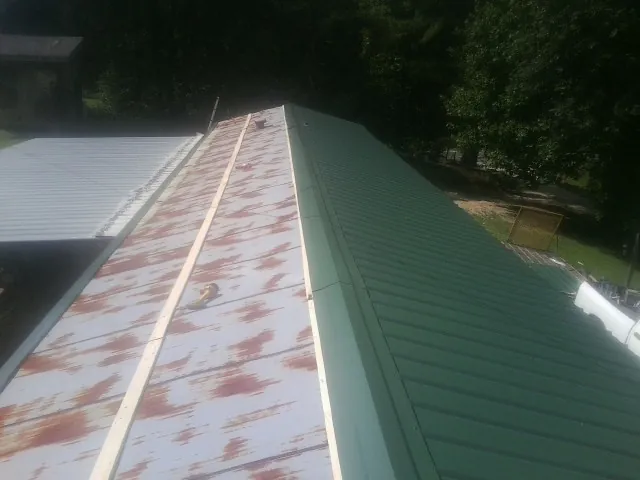 Old rusted panels beside newly installed green metal roofing — Wind Damage Roof Repair by Roofing Brothers in Tompkinsville