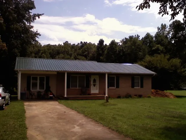 Dark green metal roof on a brick ranch with a covered porch in Tompkinsville