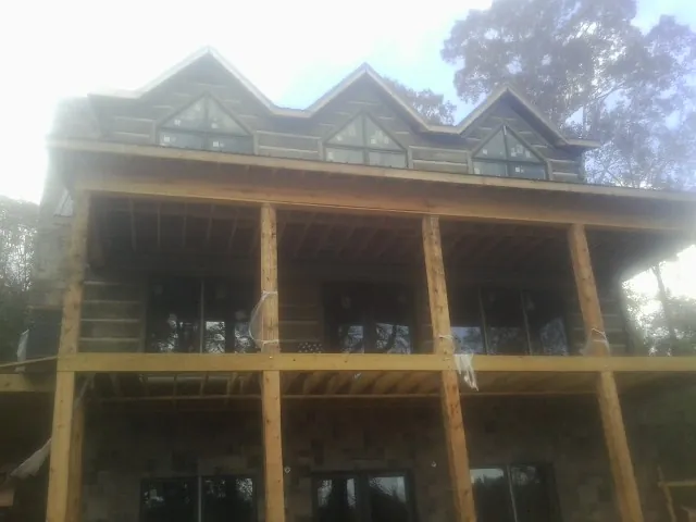 Dormers and porch framing on a large log home under construction — Roof Coating work by our crew in Tompkinsville