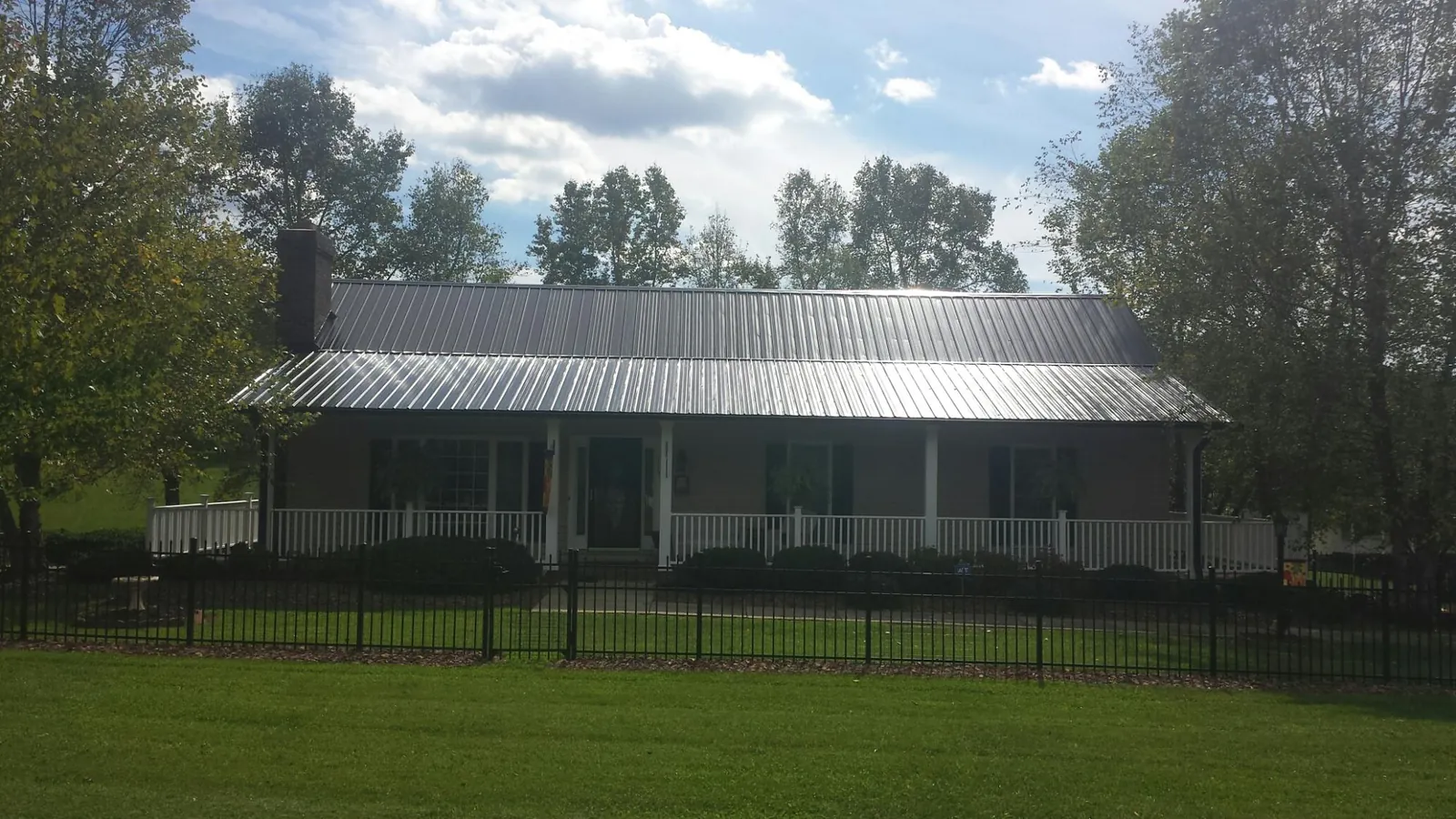 Gray metal roof on a brick ranch with a full width front porch — Gutter Guard Installation work by our crew in Tompkinsville