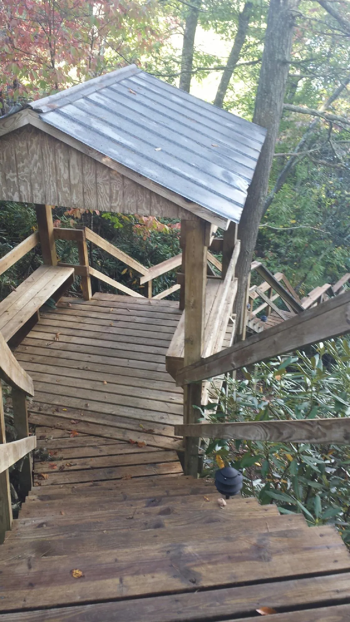 Metal roofed shelter over wooden steps on a wooded walkway — Skylight Repair & Installation work by our crew in Tompkinsville