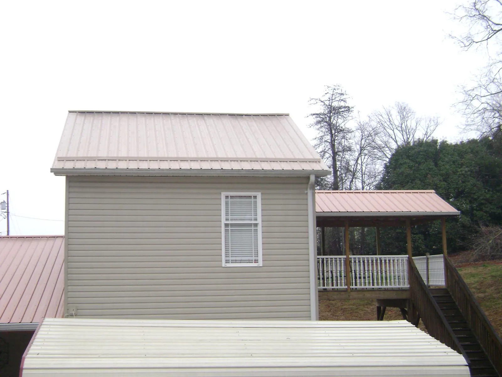 Tan metal roofs on a two story addition and attached porch, from a Roof Replacement job in Tompkinsville