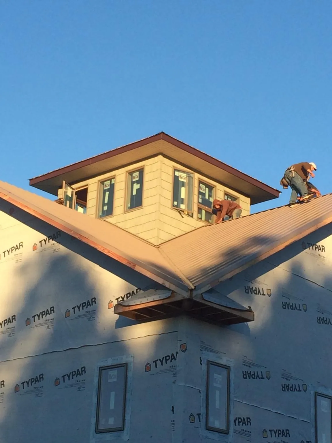 Roofers working around a rooftop cupola on a new metal roof at sunset — Roof Waterproofing in Tompkinsville by Roofing Brothers